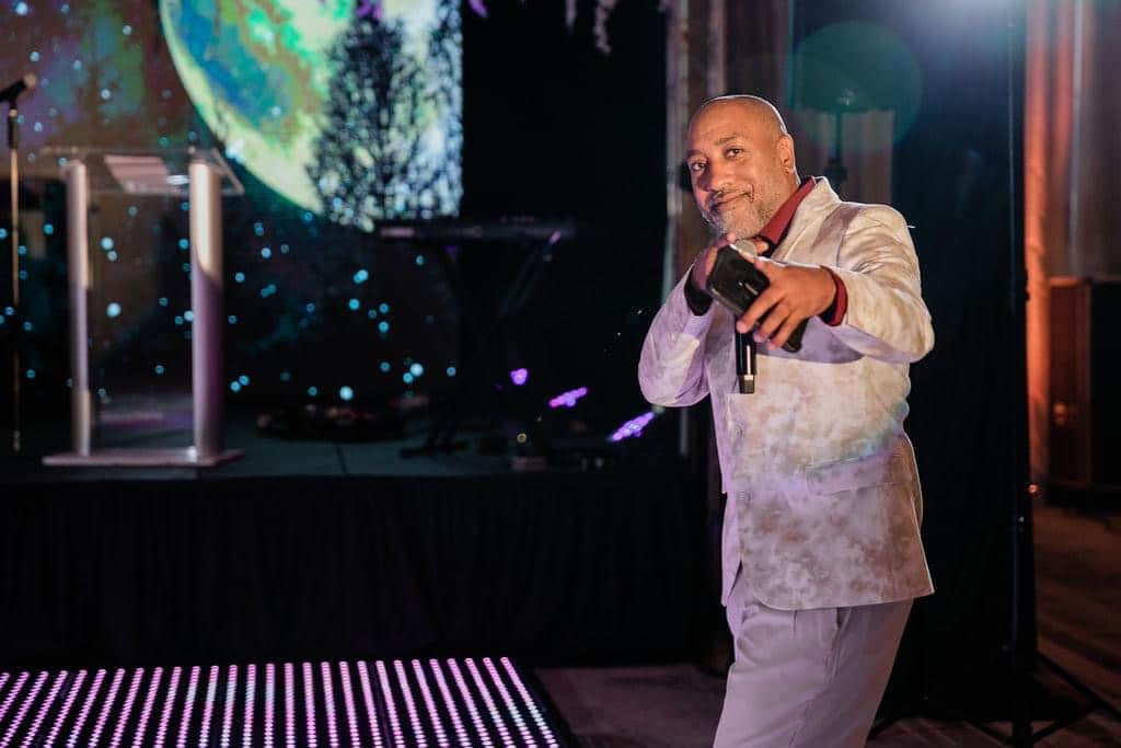 Professional DJ and MC engaging guests at a corporate or wedding event with high-energy music and professional hosting